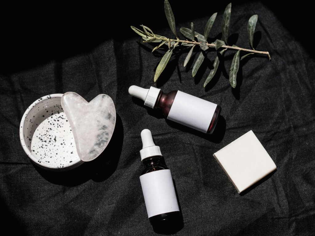 pexels-photo-8102128-8102128 Flat lay of skincare products with gua sha and leaves on black textile. Ideal for beauty and wellness visuals.